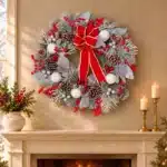 Frosted Christmas wreath with red and white decorations 75cm above an ivory mantel